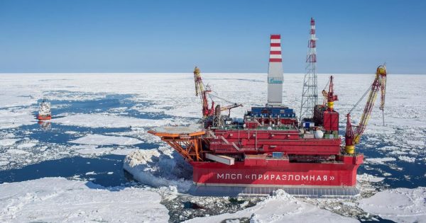 Offshore oil drilling depot oilfield “Prirazlomnaya” in sea-ice covered waters, with a blue sky.