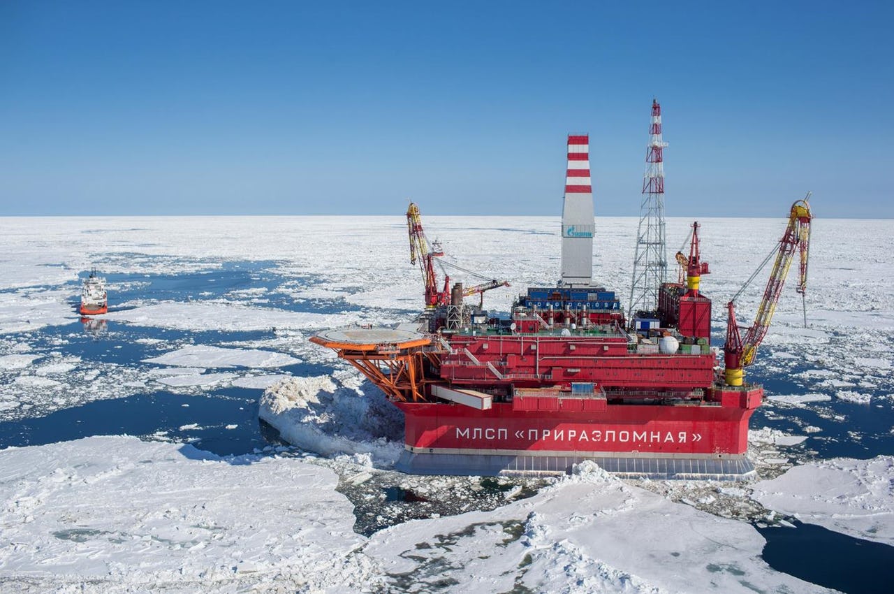 Offshore oil drilling depot oilfield “Prirazlomnaya” in sea-ice covered waters, with a blue sky.