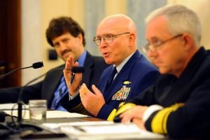 Three men in uniform talking at hearing