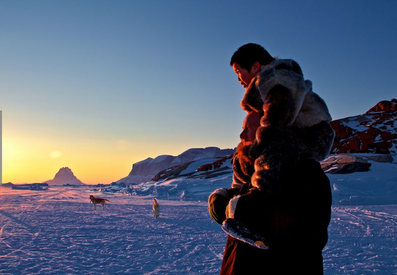 Indigenous woman standing in snow, sun is setting