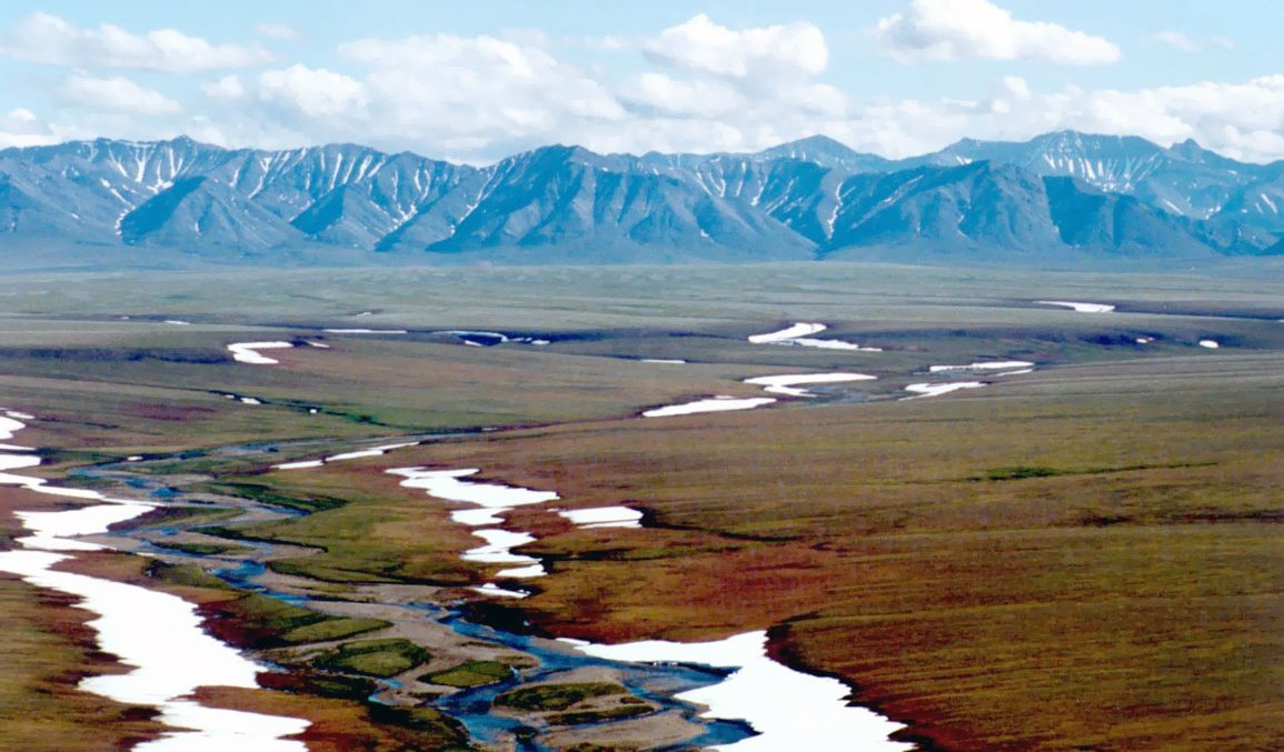 Melting snow on plain land with mountains in the background