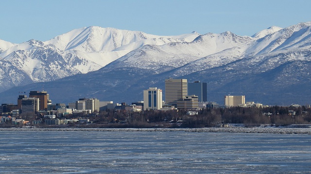 Tall buildings in downtown Anchorage with the Chugach Mountains in the background.
