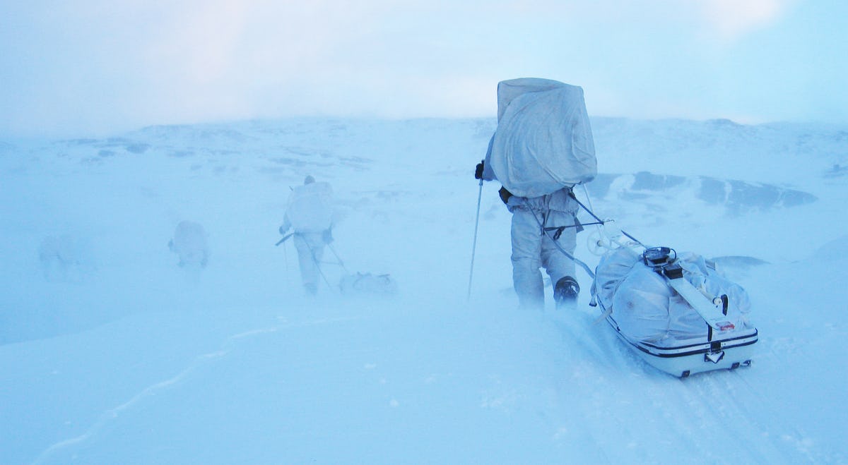 Soldiers in winter uniform walking through snowy landscape