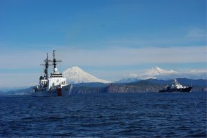 Two vessels on ocean with snowy mountains in the back