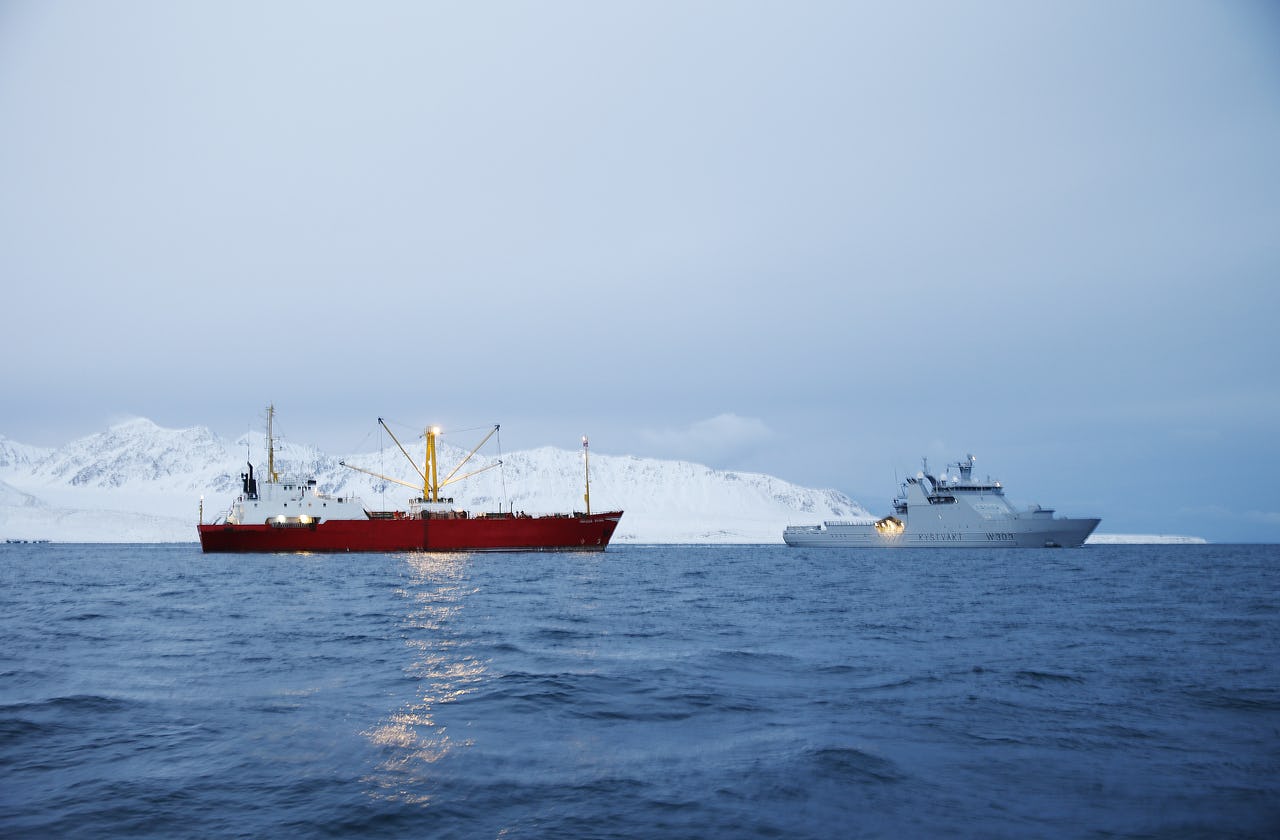 Two vessels on sea with snow mountain as background