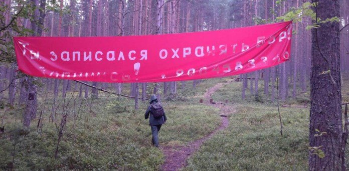 Person walking on forest path under big red banner