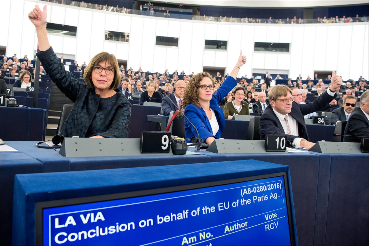 Members of Parliament vote by raising their arms