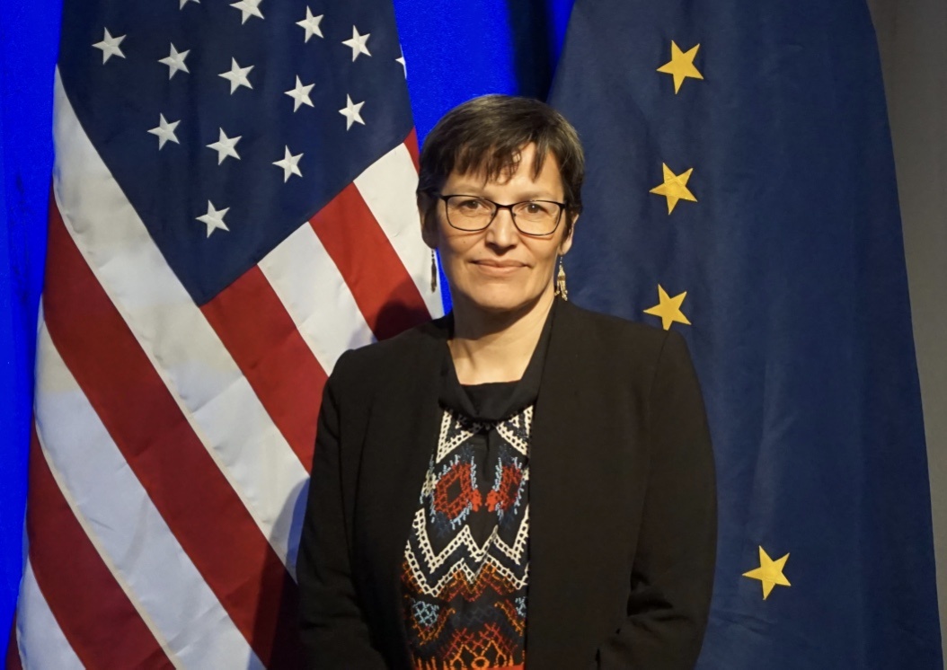 Greenland's Minister of Foreign Affairs, Suka K. Frederiksen, which is part of the Danish delegation to the Arctic Council stands in front of the Stars and Stripes and the Alaskan flag