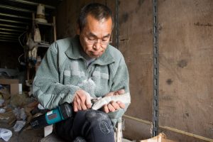 A man carving a sculpture out of a moose antler