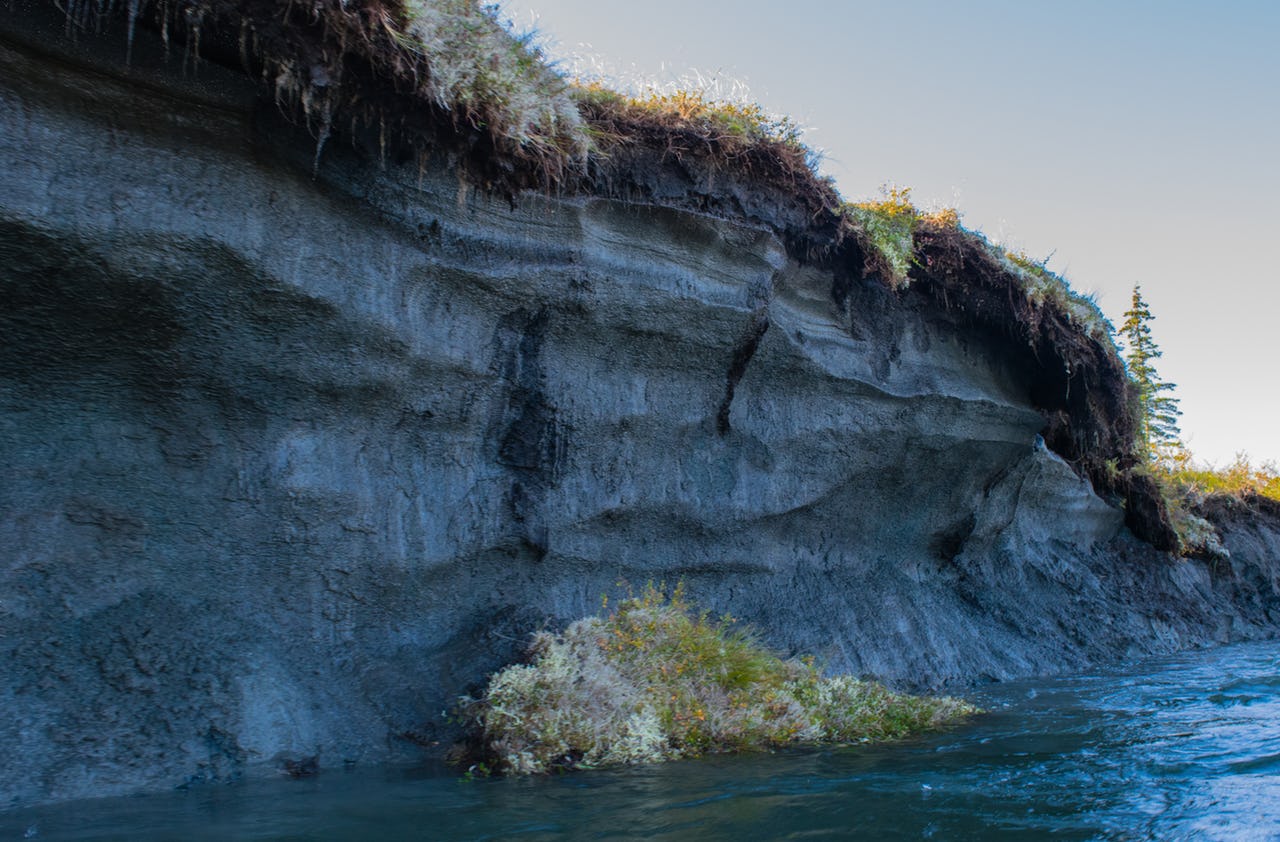 Exposed permafrost at a river with water floating by