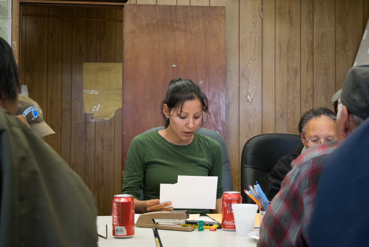 Woman reading from a paper while sitting at a table