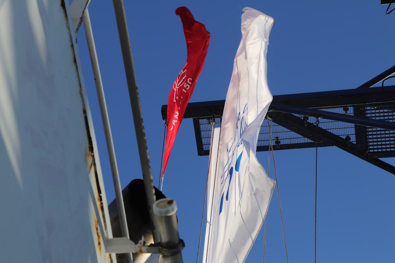 Flag flying on top a ship against blue sky.