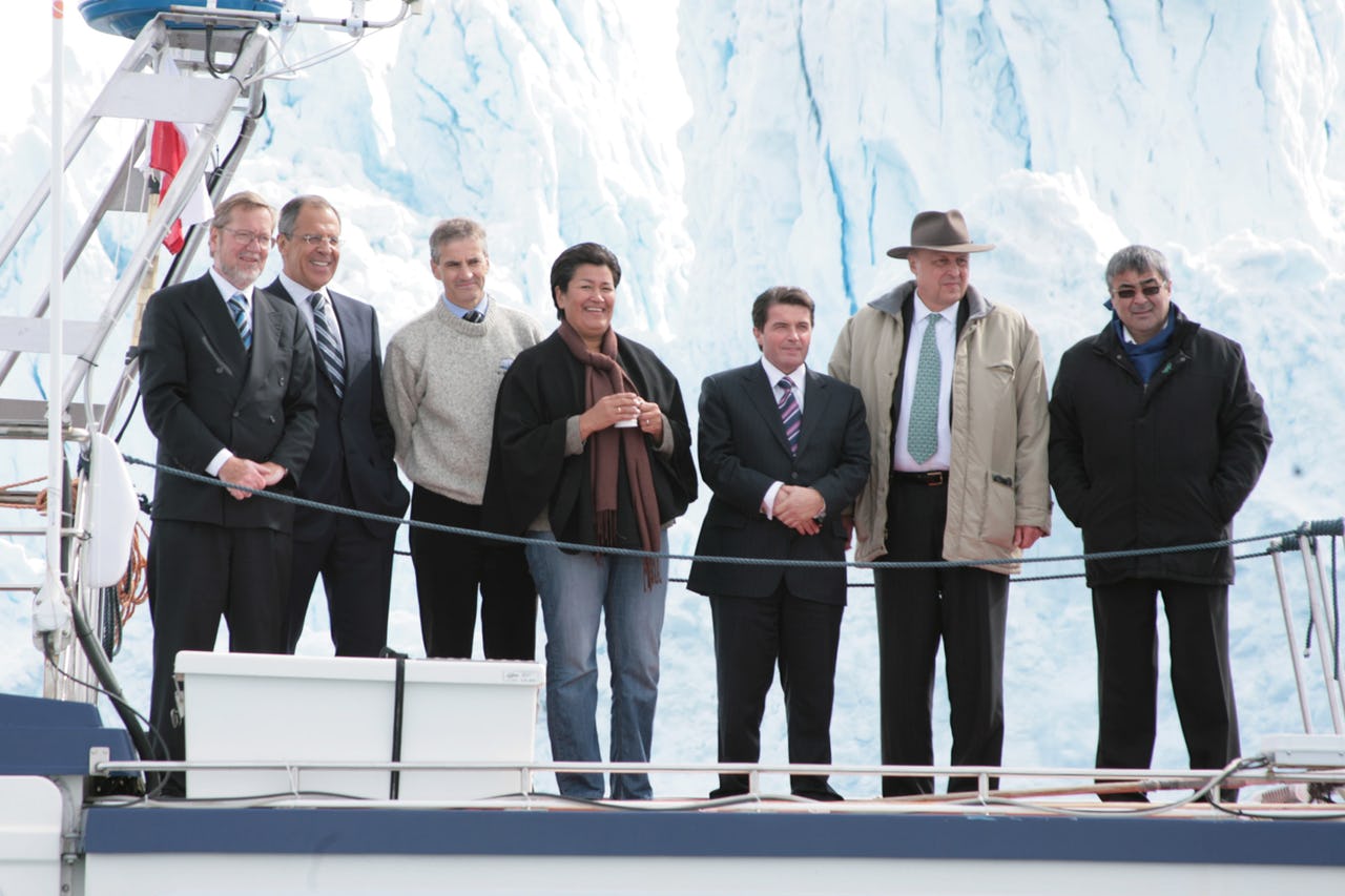 Seven people standing in front of an iceberg on a ship