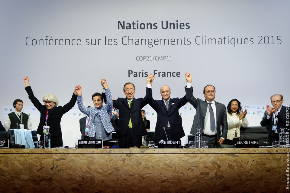 Five people at a table holding hands in the air