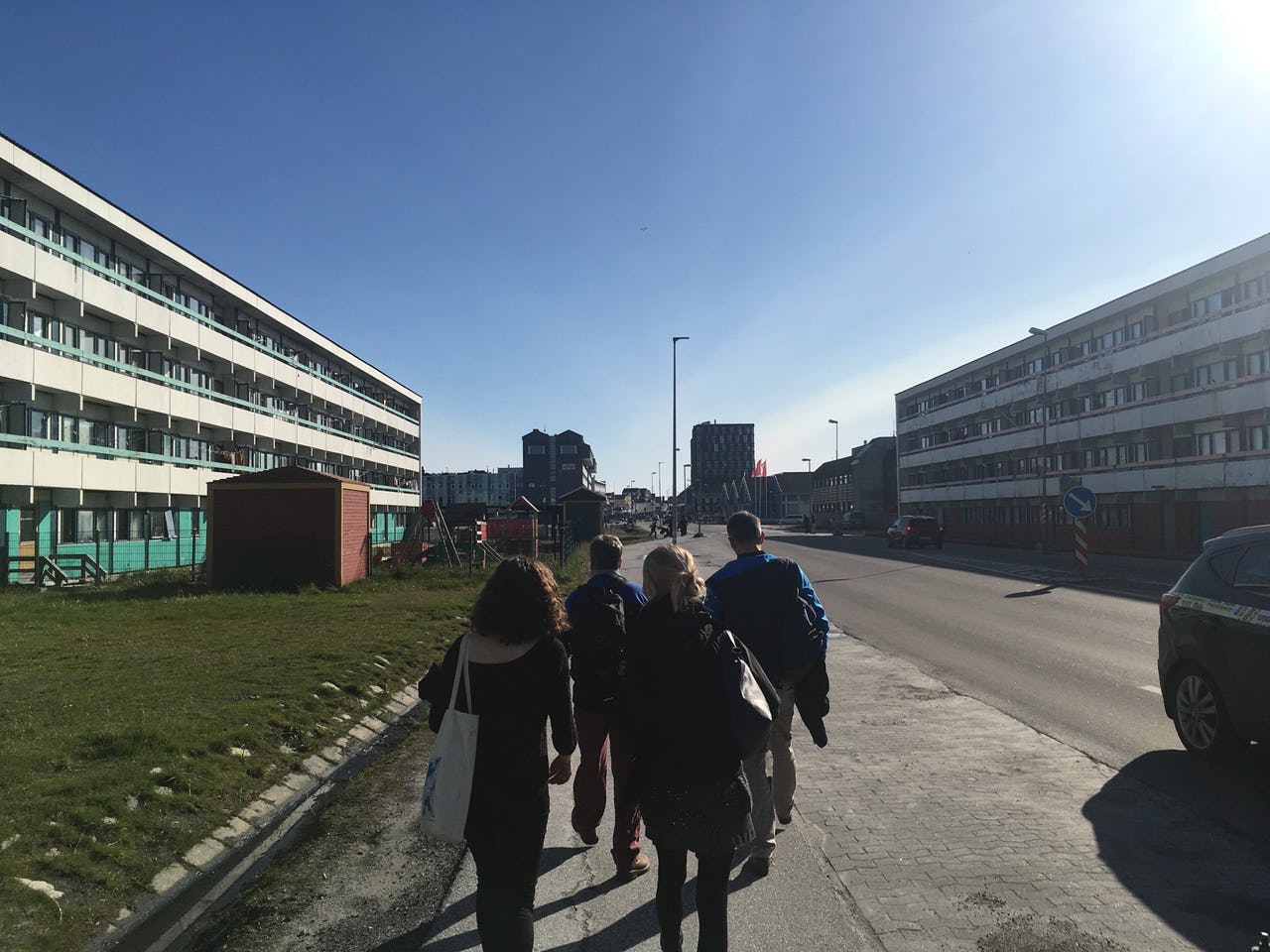 People walking down a street with residential houses on each side.