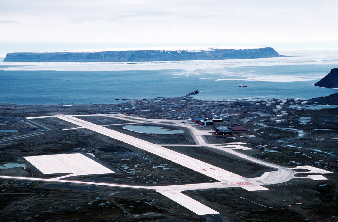 Aerial view of a landing strip with water and mountain in the background.