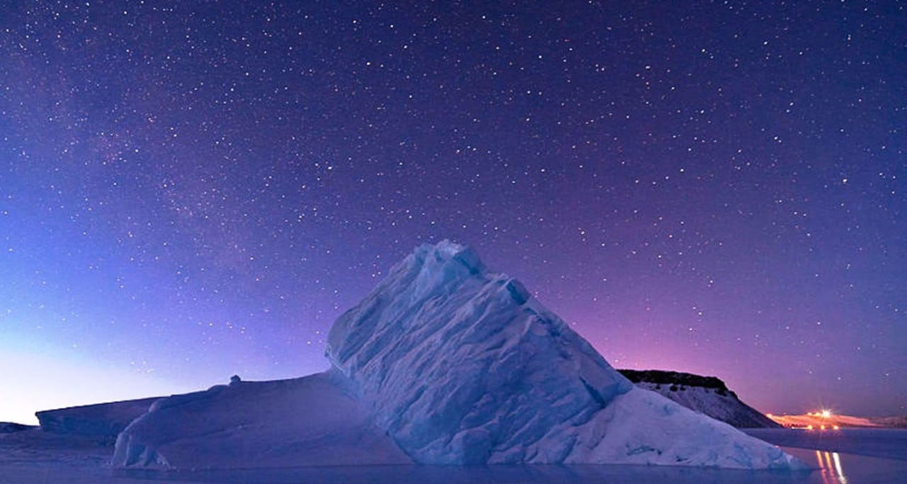 Iceberg floating against a sky with lots of stars