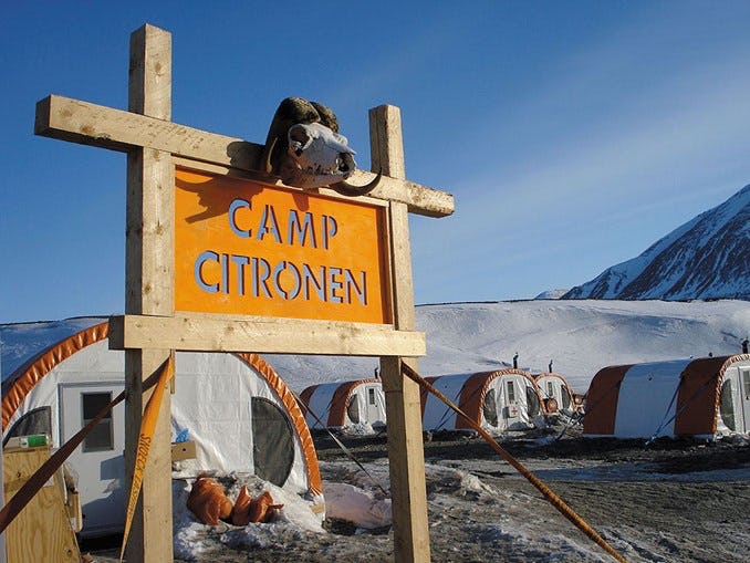 Orange sign saying “Camp Citronen” on it with tents and blue sky in the background