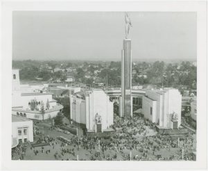 Black and white photo of a huge building with a high statue in front of it