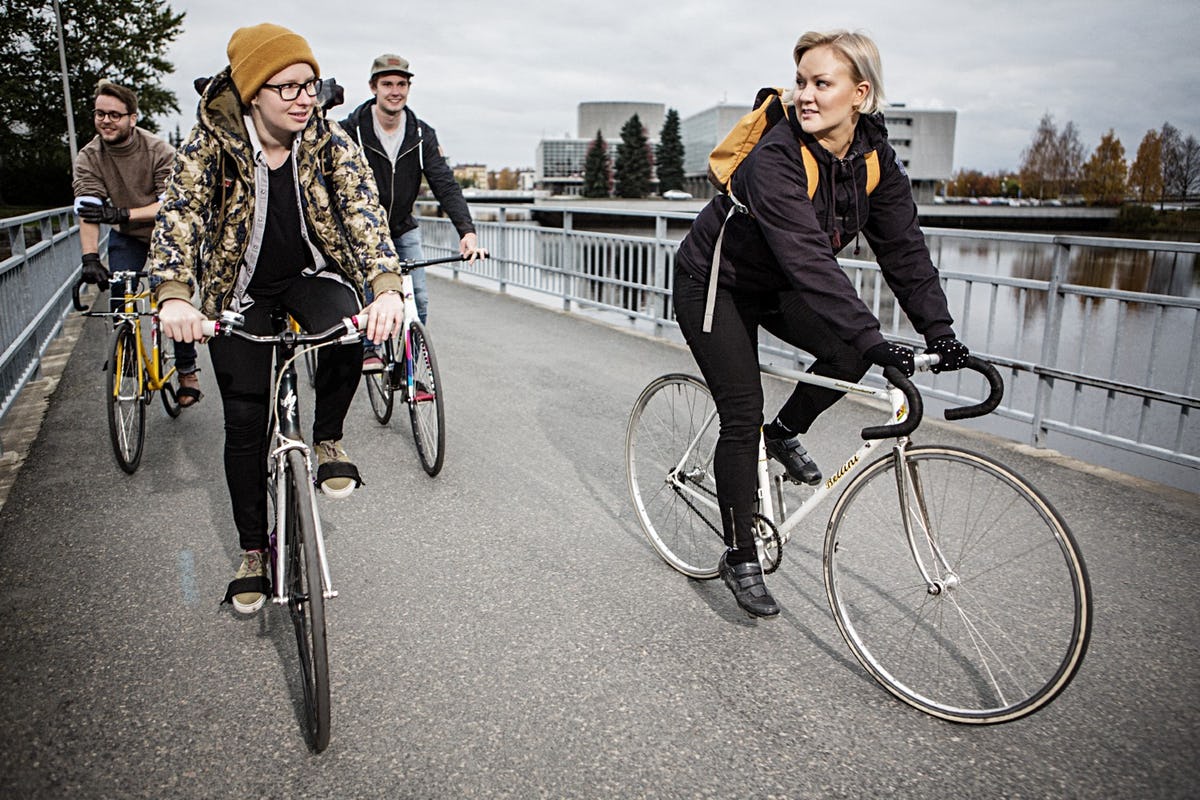 Four people on bikes cycling over bridge