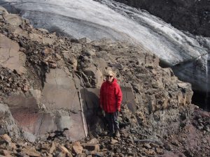 Woman with red jacket in rocky, icy landscape