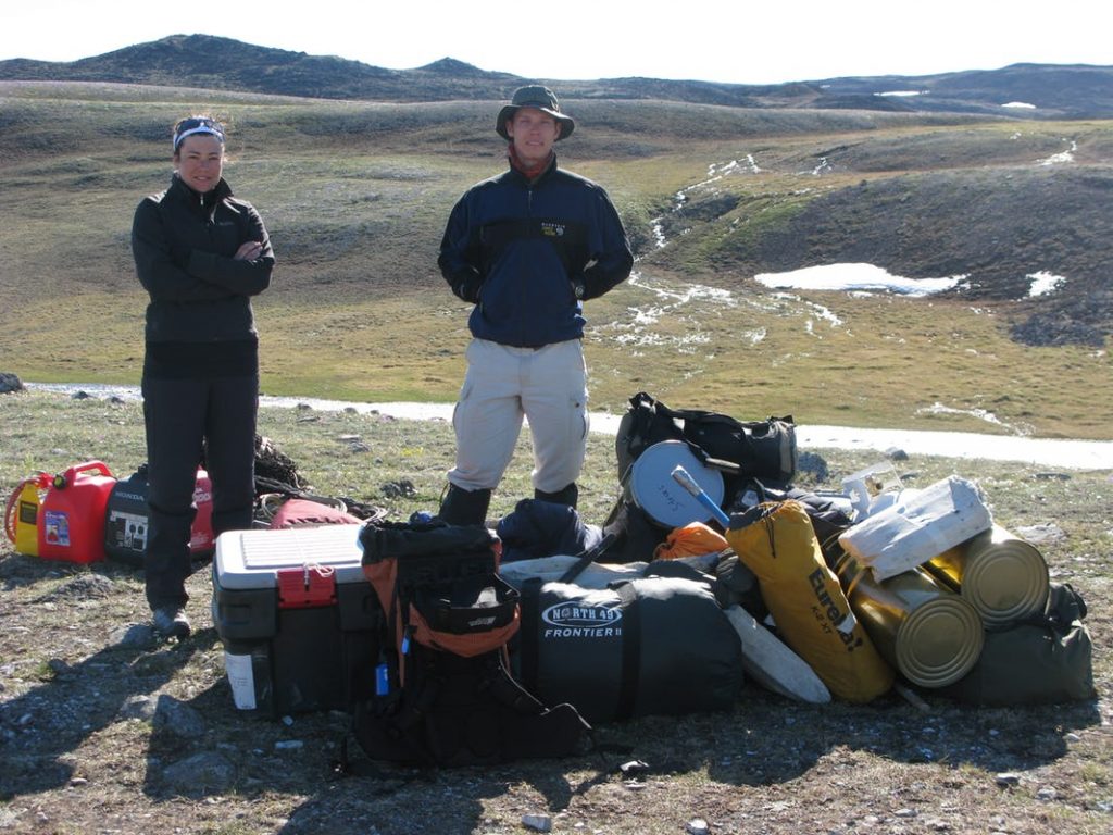 A man and a woman with hiking gear against a barren landscape