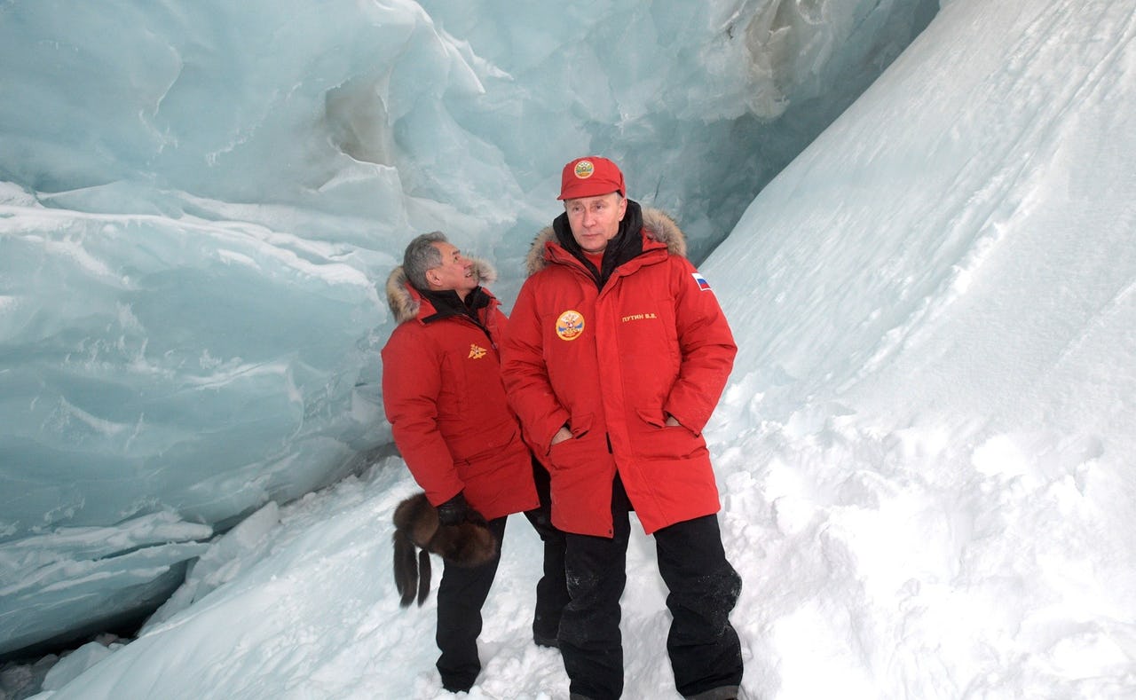 Two men dressed in red winter coats on ice glacier iceberg on an Arctic island