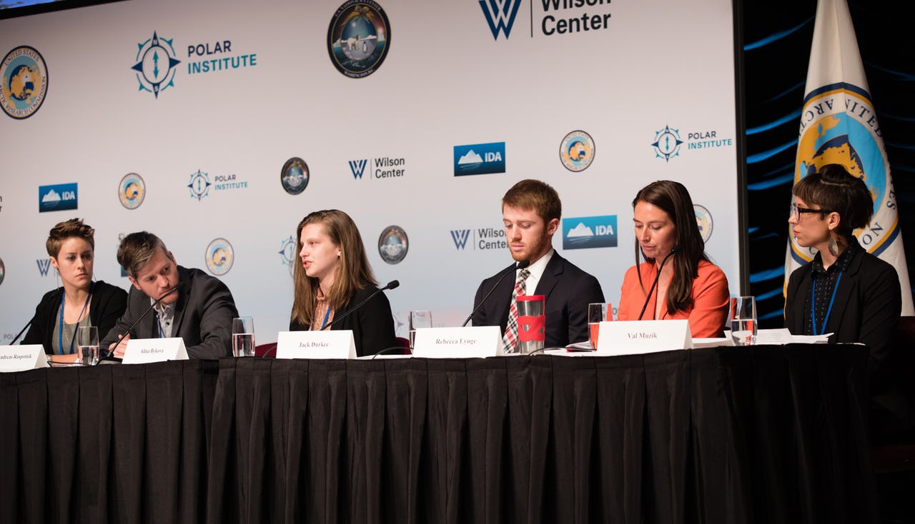 Four women and two men sitting on a panel at a conference