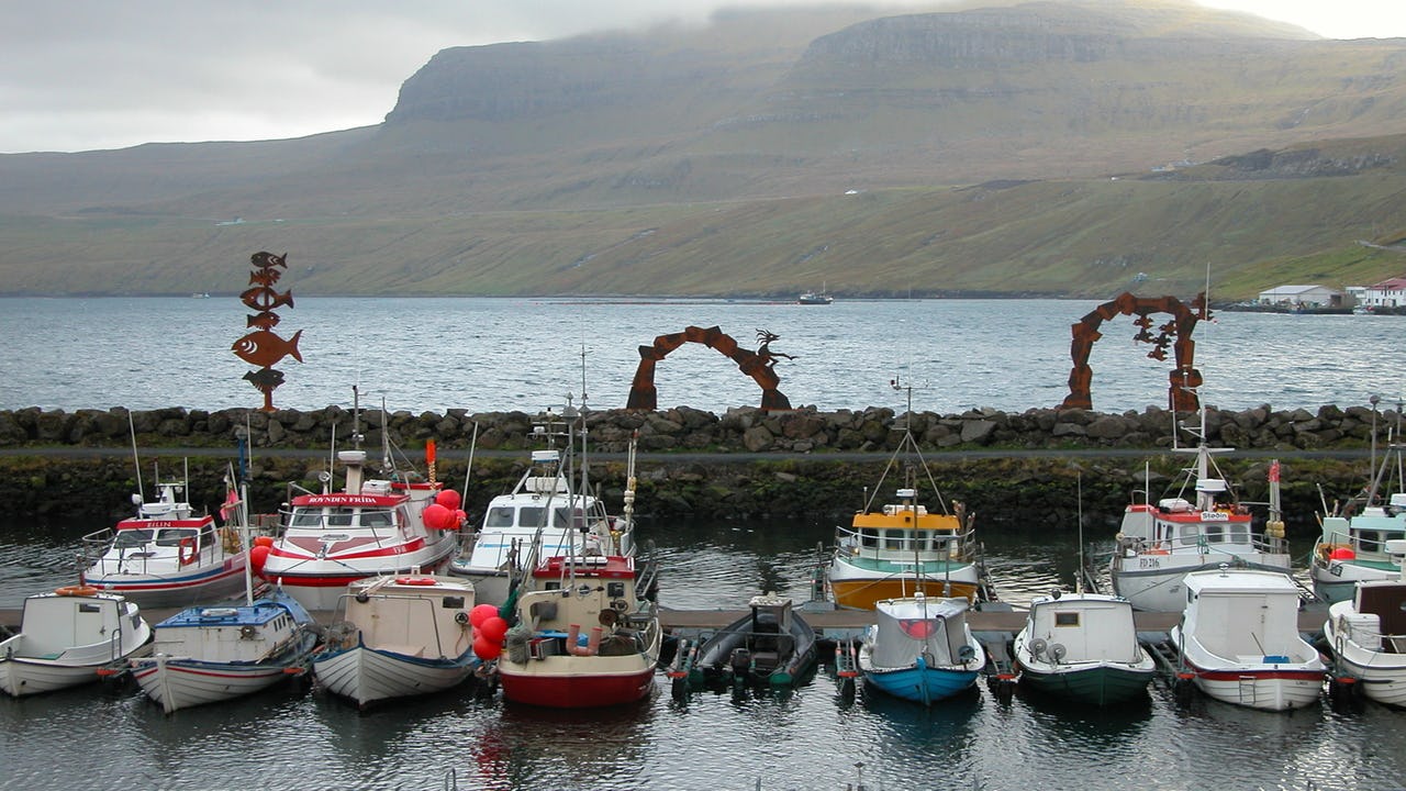Fishing boats moored in a protected harbour in a fjord in the Faroe Islands