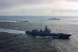 Grey navy ships and submarine on grey ocean