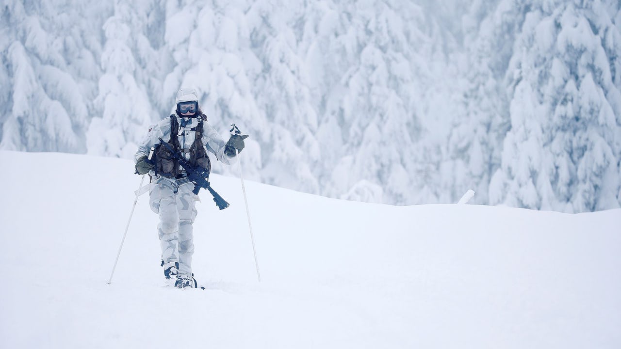 Women Norwegian soldier on skis in snow with white background