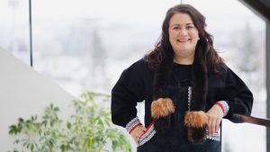 An Alaska Native woman wearing a traditional atikluk smiles for the camera