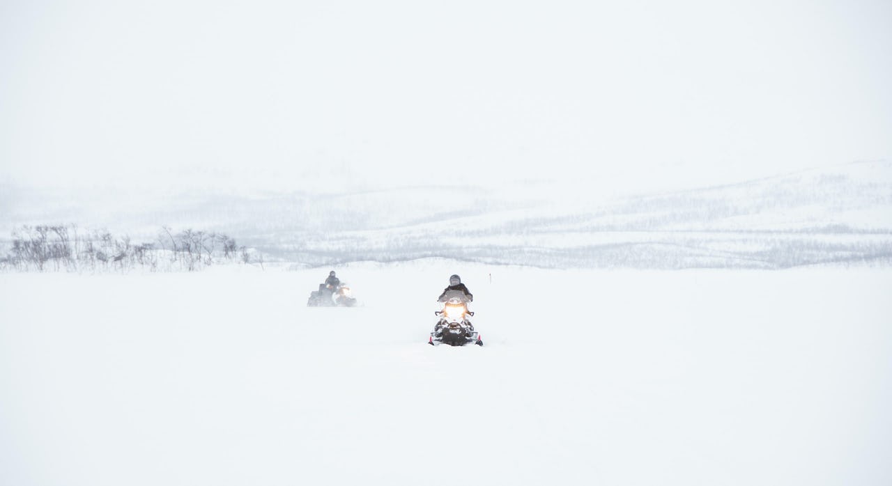 Woman on snowmobile with snow-covered moutains in the back