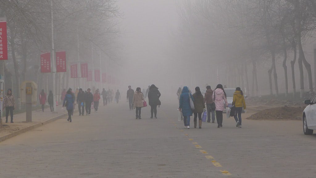People walking on street in a dense air pollution environment