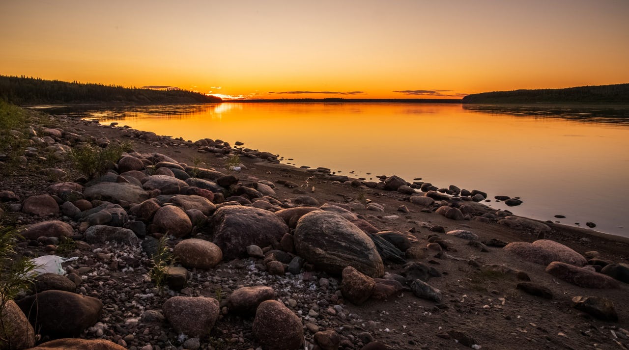 Sunset on water with rocks and mountain