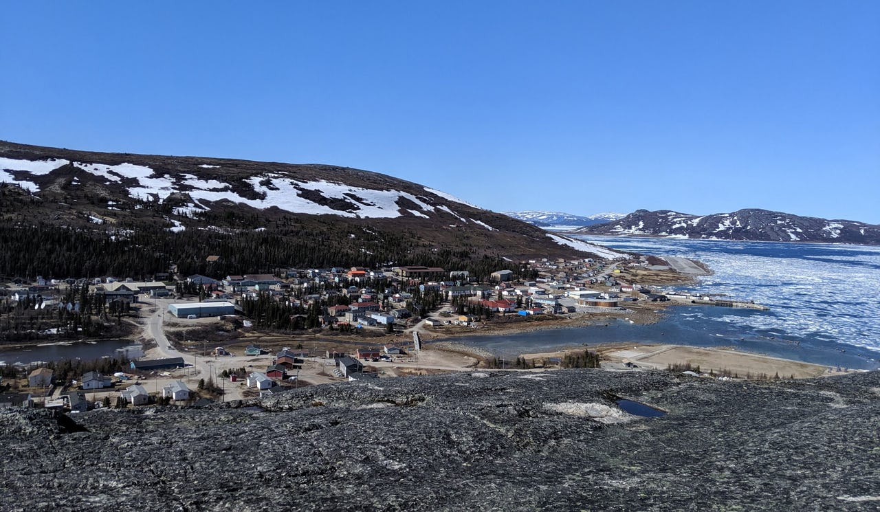 Houses next to water with ice and mountains in background