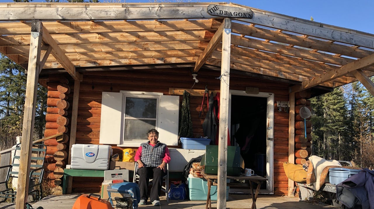 Woman sitting in a chair on front porch of log cabin