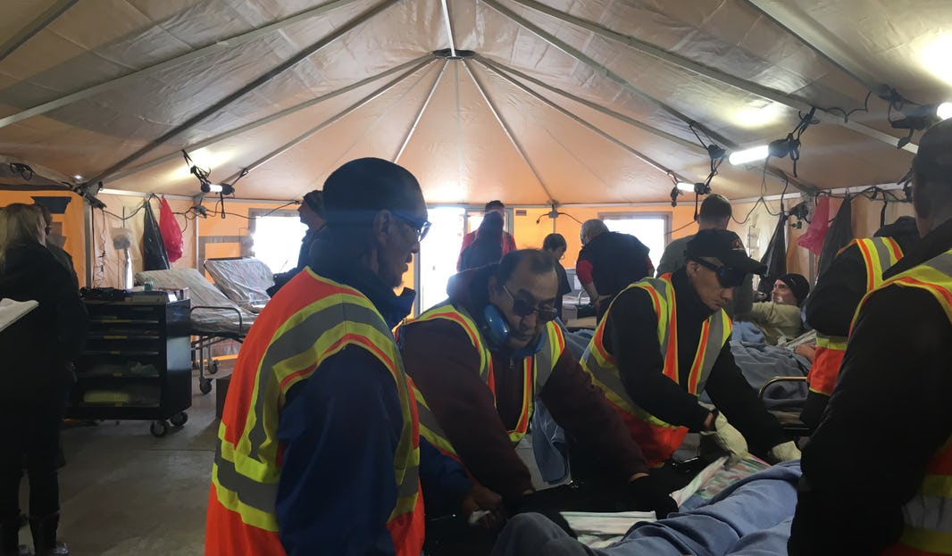 Several men in rescue outfits helping another person