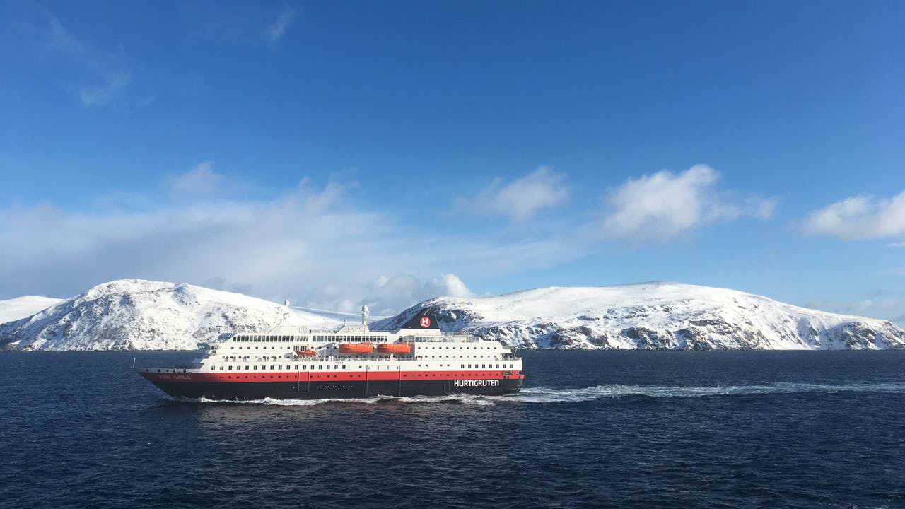 Hurtigruten cruise boat along the coast of Northern Norway and mountains covered in snow