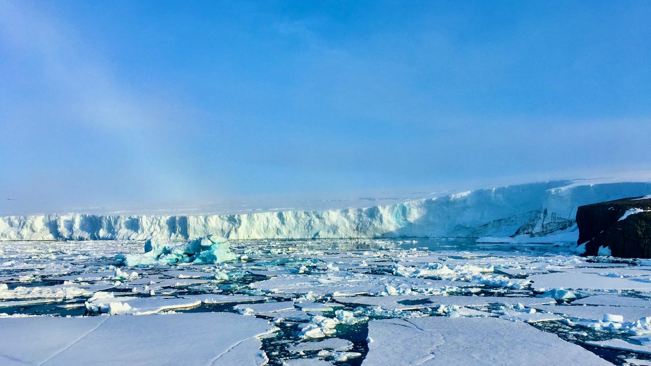 A glacier covering Champ Island on Franz Josef Land with ice-free rocky cliffs and floating sea ice