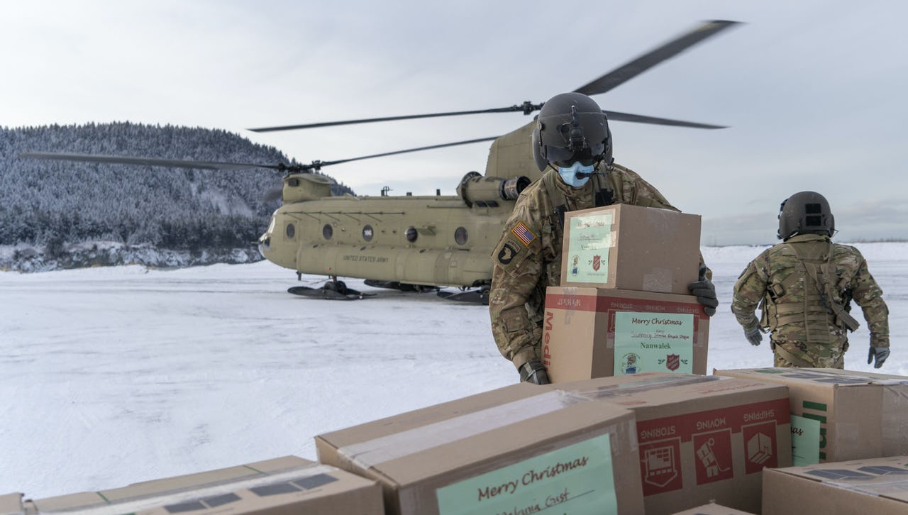 Soldiers wearing face masks while packing a helicopter standing on a snowy underground