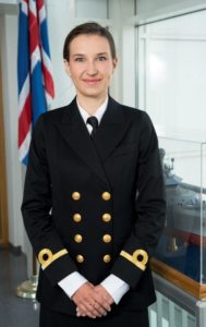 Woman in navy blue Icelandic coast guard uniform with Icelandic flag in the background