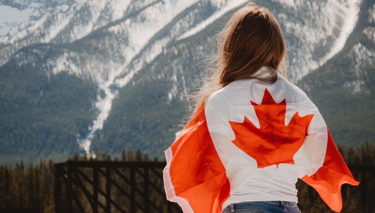 Woman with Canadian flag around her neck looking at mountains