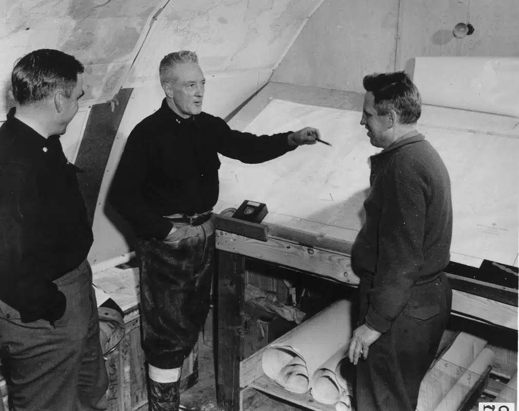 Black and white image showing three men in a research camp in Antarctic