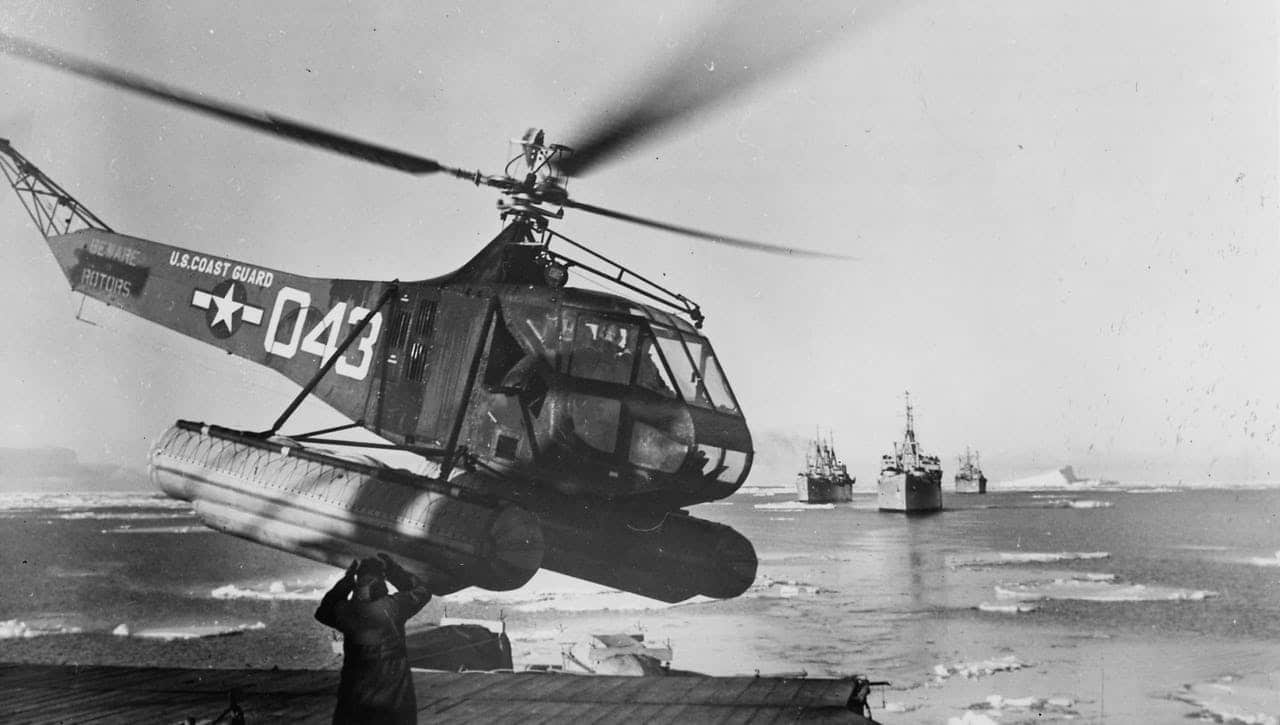 Black and white image showing a Coast Guard helicopter landing on the deck of an icebreaker in Antarctic