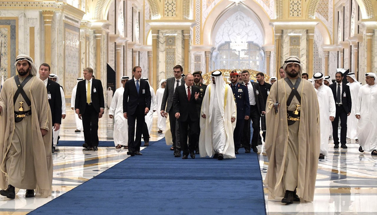 Two men - Vladimir Putin and Mohamed bin Zayed - walking alongside their entourage in Qasr Al Watan Palace