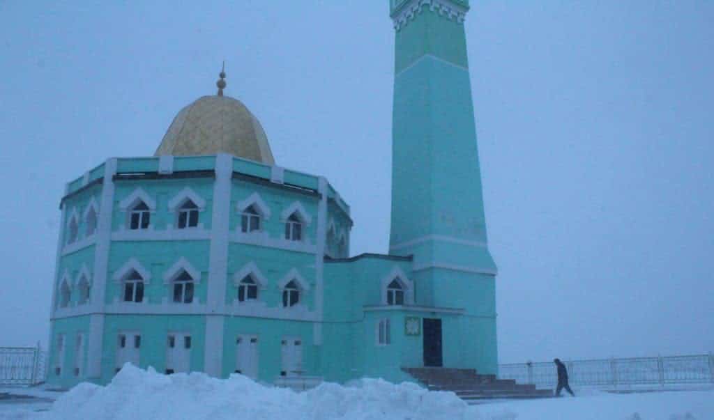 A person is entering a blue mosque with snow all around