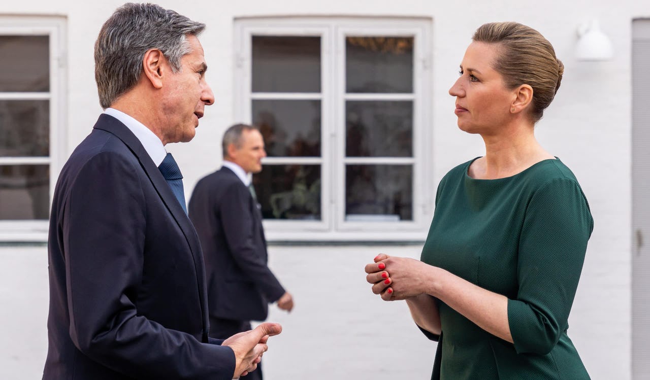 A man and a woman talking to each other in front of a white house