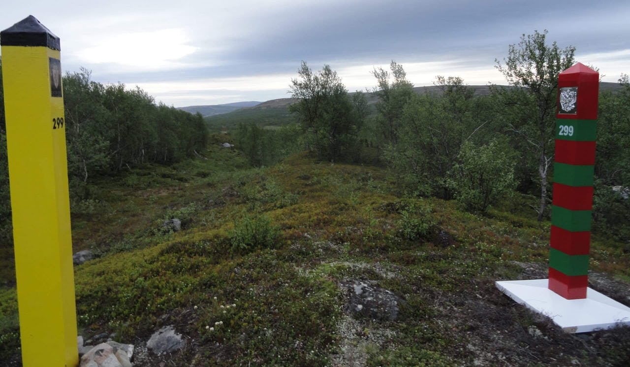 Poles in forest in Arctic landscape separating land between two countries