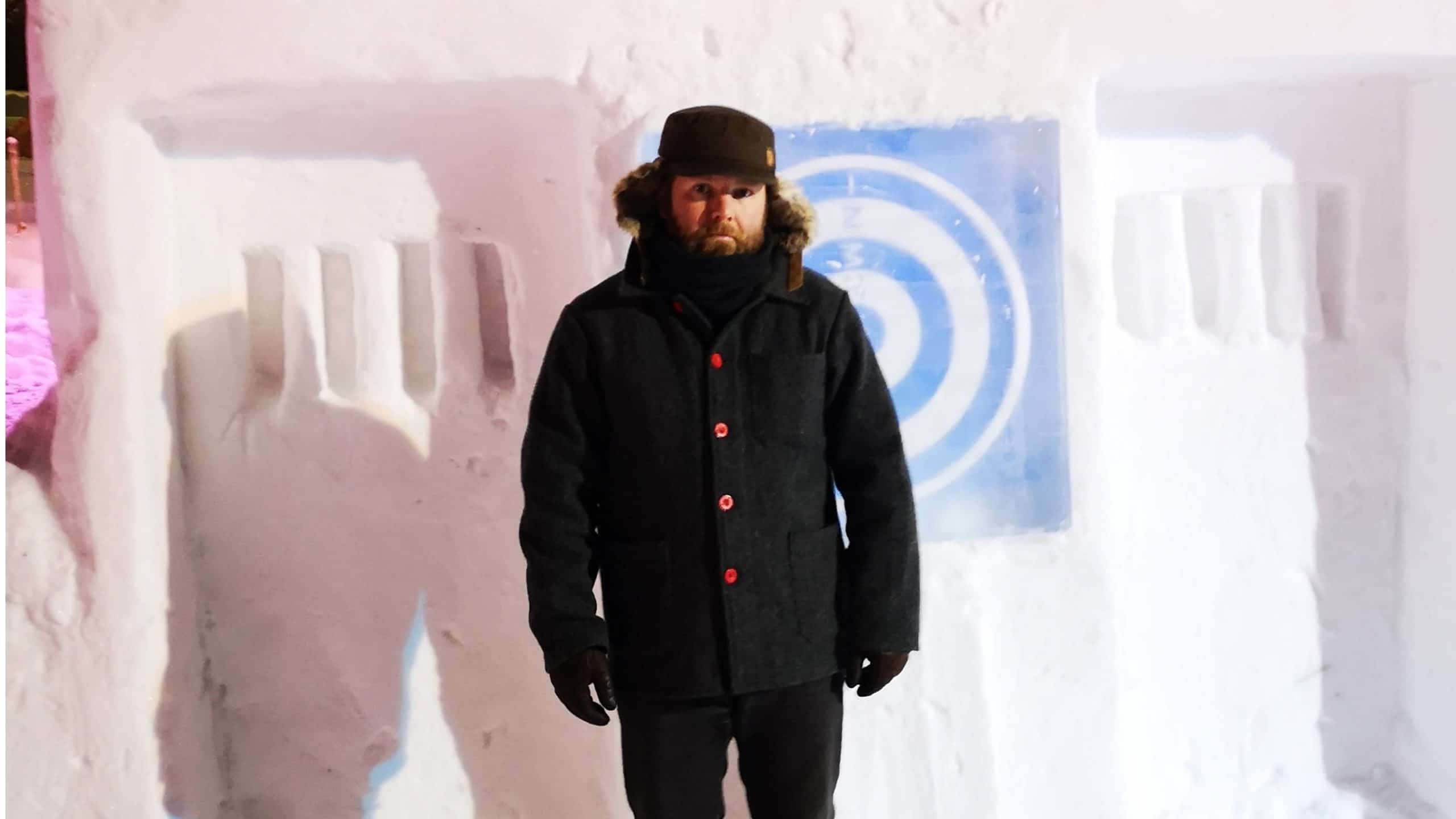 Eric Boyd wearing black winter clothes in front of a snow sculpture